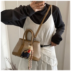 Detail of canvas bucket bag with brown leather trim and cute teddy bear charm