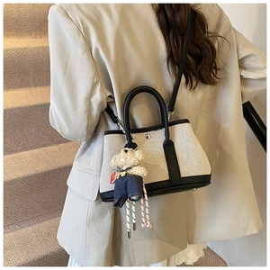 Canvas tote bag with black leather trim, elegant shoulder strap and cute bear charm.