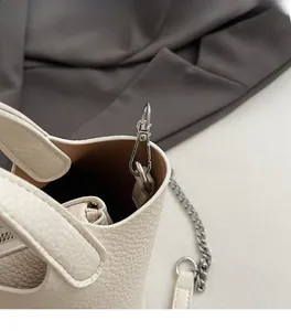 Close-up of the silver metal hook and pebble leather texture on a beige bucket bag