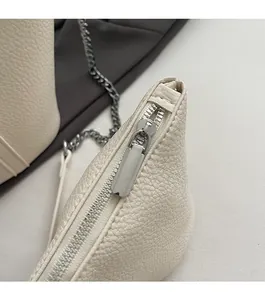 Detailed close-up of smooth silver zipper and lychee grain leather on beige bucket bag