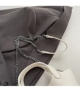 Close-up of white bucket bag with pebble leather texture and silver chain strap details