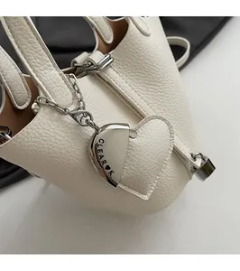 Detail of white lychee leather texture with silver chain and heart-shaped logo pendant