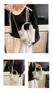 Detailed macro view of beige lychee leather bucket bag with silver chain strap and heart charm