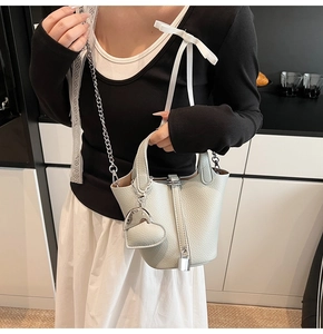 Close-up of litchi texture bucket bag with metal chain strap and heart charm