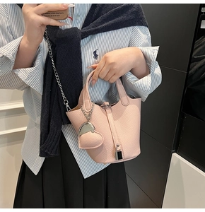 Detail of pink lychee grain leather bucket bag with silver lock and heart charm