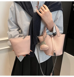 Pink lychee texture leather bucket bag shown on a model with heart pendant and inner pouch