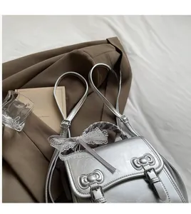 Detail of silver matte handbag with metallic bow buckles and grey lace ribbon decor