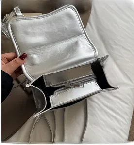 Detail view of smooth metal zipper and spacious interior lining of silver fashion bag