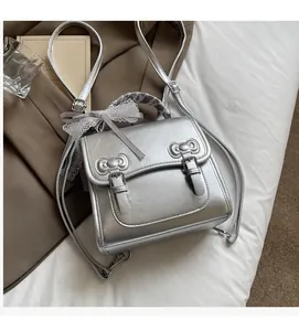 Close-up of metallic silver mini backpack with ribbon lace handle and bow buckles