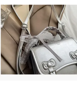 Detail of silver faux leather handbag featuring metal bow buckle and purple lace ribbon