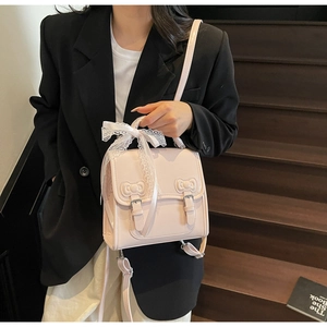 Detailed view of light pink PU leather mini backpack with lace bow and metal buckles