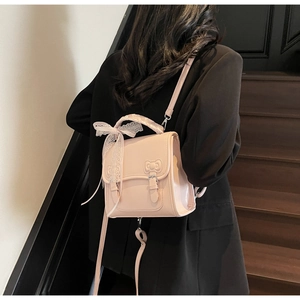 Detail of pink PU leather mini backpack with bow pattern and white lace charm