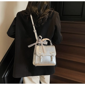 Silver metallic backpack with double buckle straps and lace bow ribbon detail