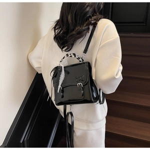 Detail of glossy black backpack featuring bow embossing and silk scarf handle