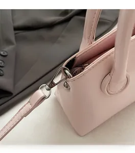 Detail of pink leather handbag with silver hardware clasp and detachable shoulder strap