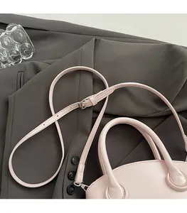 Close-up of pink bowling bag with adjustable shoulder straps on a gray suit
