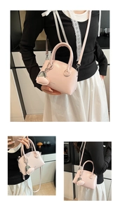 Detail view of pink glossy handbag with metal heart charm and clear brand logo print