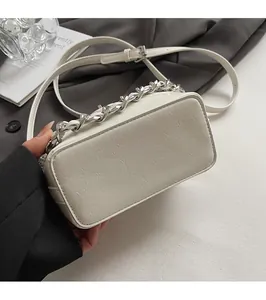 Dettaglio del fondo piatto e della trama in pelle di una borsa a tracolla beige chic