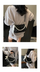 Detail of black pleated crossbody bag with pearl handle and lace bow decoration