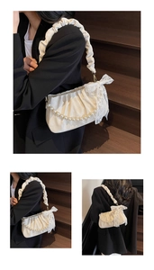 Detail of white pleated cloud bag featuring pearl chain and delicate lace bow