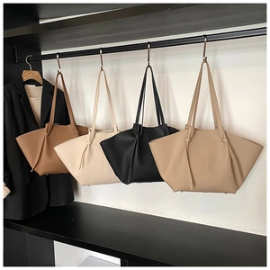 Detail view of four large wing-style tote bags in different colors hanging on a rack