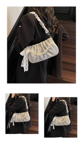 Silver-grey pleated satin shoulder bag with pearl chain and lace bow on a model