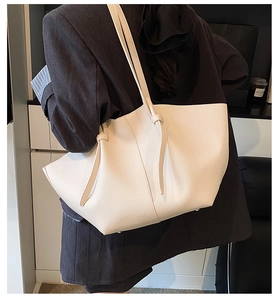 Detail view of cream tote bag with litchi grain texture and elegant handle knot