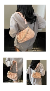 Detailed view of pink satin pleated bag with pearl strap and white lace trim