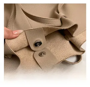 Detailed macro view of magnetic clasp and fine stitching on a beige litchi leather bag