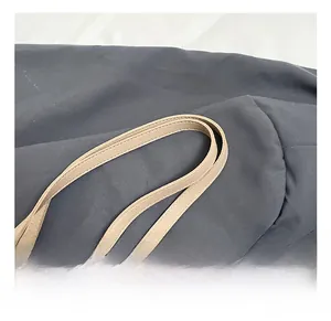 Close-up of the beige tote bag handle featuring premium lychee texture and dual stitching