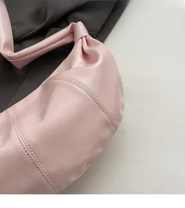 Detail of pink faux leather hobo bag showing fine texture and knotted shoulder strap
