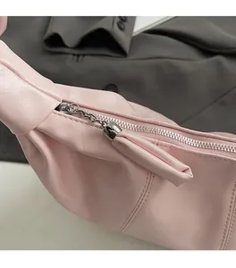 Detail of a smooth silver zipper and leather tassel on a pink dumpling bag