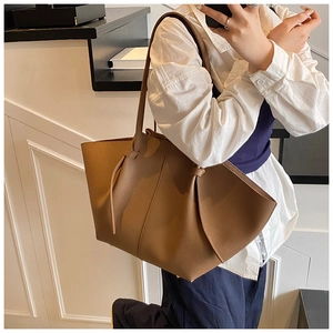 Close-up of caramel brown tote bag showing lychee grain leather and wing-shaped side detail