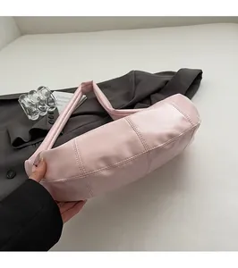 Detail shot of light pink leather dumpling bag with decorative stitching on a blazer
