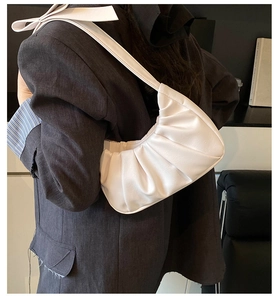 Détail du sac plissé en crème avec un nœud élégant sur la bandoulière pour un look chic