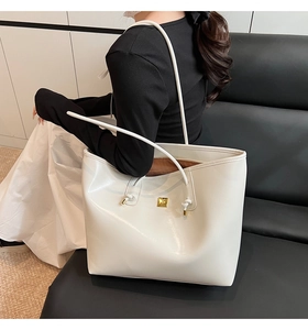 Detailed side view of white faux leather tote bag with gold buckle on shoulder
