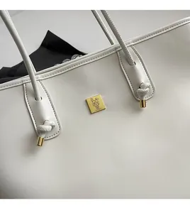 Detail of white PU leather tote bag showing soft texture and gold square logo buckle