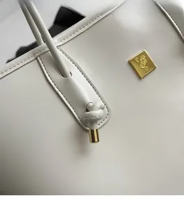 Detailed view of cream leather shoulder bag featuring lychee texture and gold rabbit logo