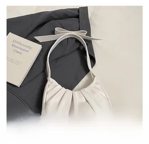 Détail du sac nuage plissé blanc avec nœud élégant sur fond de costume gris chic