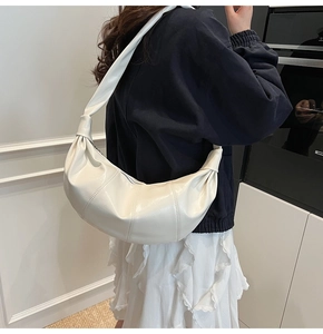 Detail showing cream semi-moon bag with leather pleats and knotted shoulder strap detail