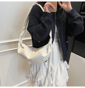 Detail view of cream white crescent bag with pleated PU leather texture and thick strap