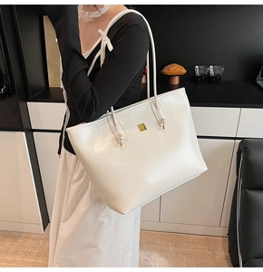 Detail of white tote bag with glossy leather texture, knotted strap and gold hardware
