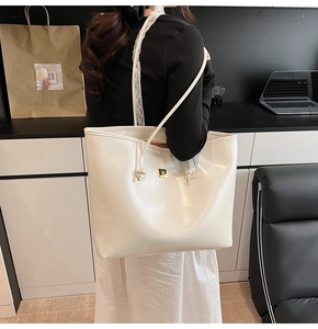White glossy tote bag detail with golden buckle and delicate lace shoulder strap accents