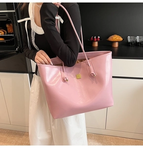 Detail of pink tote bag with golden logo plaque and elegant knot handles decoration
