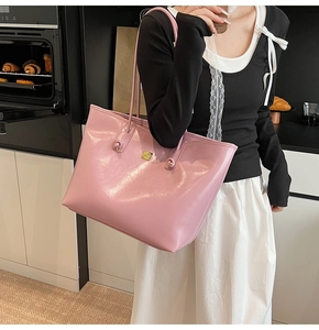 Pink glossy faux leather tote bag with gold buckle detail shown in lifestyle setting
