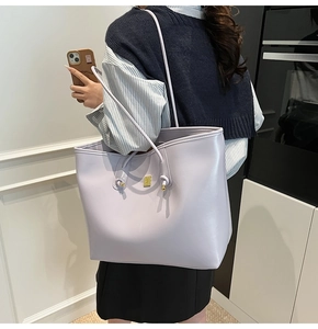 Detail view of large lavender faux leather tote bag showing smooth texture and logo