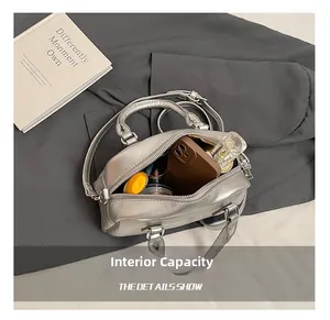 Internal capacity of silver boston bag showing phone, perfume and cosmetics storage