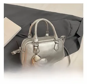 Detail show of silver bowling bag with metallic heart charm and adjustable strap