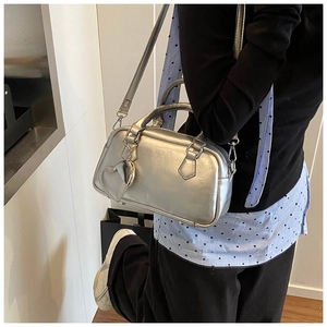 Silver metallic bowling bag shown with detachable strap and heart mirror detail on a model