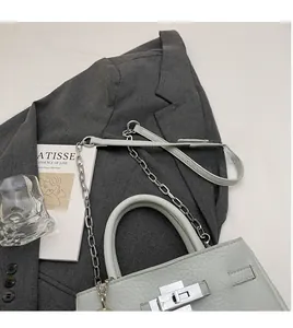 Detail of light grey leather bucket bag featuring silver twist lock and chain strap